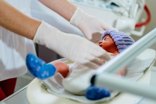 Pediatrician weighing a premature newborn during a neonatal health assessment