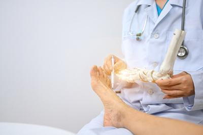 Foot specialist explains diagnosis using skeletal model to male client