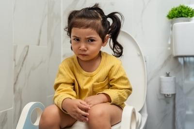 Young girl suffering from constipation sitting on toilet