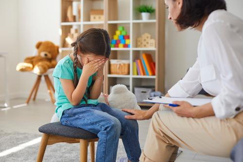 Anxious child shy about talking to pediatrician during routine screening.