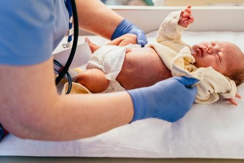 A pediatrician providing care and examination for a newborn baby.