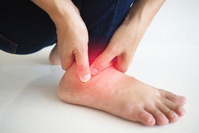 Person-holding-ankle-in-pain-highlight-in-red.