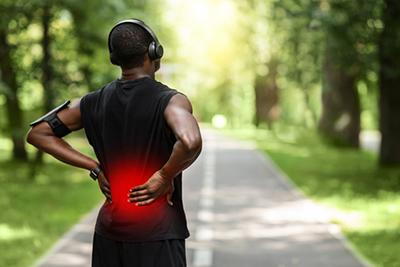 Male experiencing back pain during outdoor activity