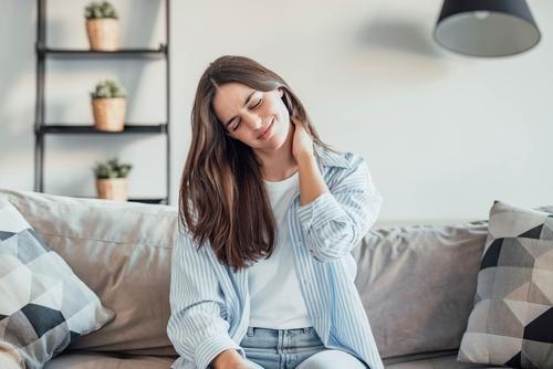 Woman suffering from neck stiffness at home