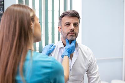 Male patient undergoing head and neck cancer examination by ENT specialist