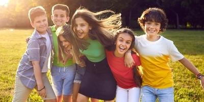 Smiling-Kids-Hugging-Outdoors-In-a-Sunny-Green-Park