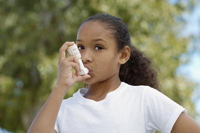 Young girl using an inhaler on her mouth.