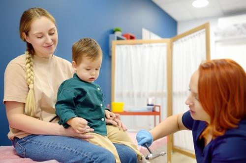 Pediatrician assessing toddler's motor skill development while mother holds child