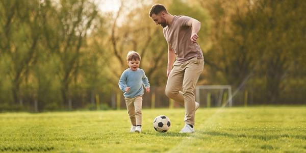 A father encouraging his son to engage in physical activity by playing soccer together.
