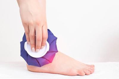 Woamn-with-Swollen-Ankle-Uses-Ice-for-Treatment