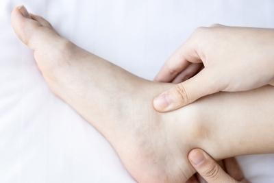 Hand Examining Swollen Flat Feet  in Discomfort