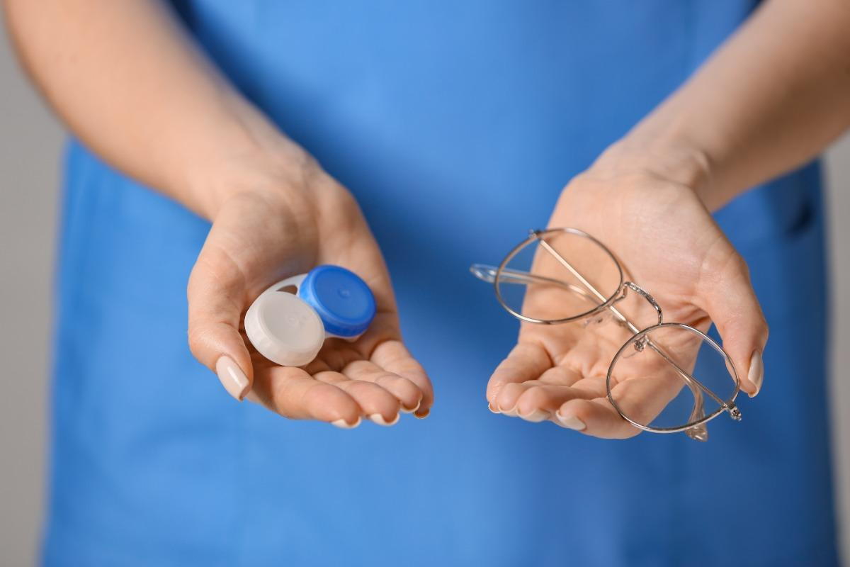 Someone holding contact lens and eyeglasses