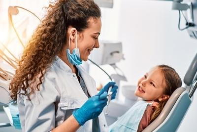 Dentist check the little girl teeth on dental chair on clinic.