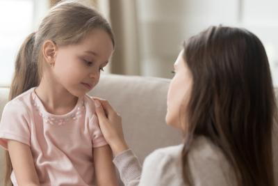 Mother talking sincerely to her young girl on sofa.