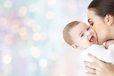 Smiling baby with her mother kiss