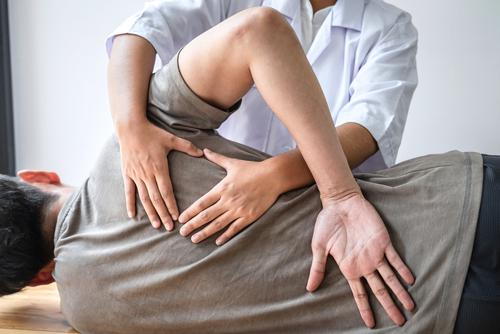 Chiropractor treating a male patient’s back pain.