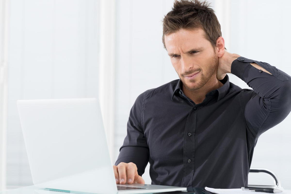 This is a photo of a man with neck pain looking on his computer for our Killeen Chiropractors
