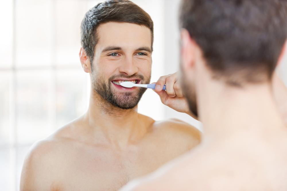 Man brushing his teeth before a visit to the dentist.