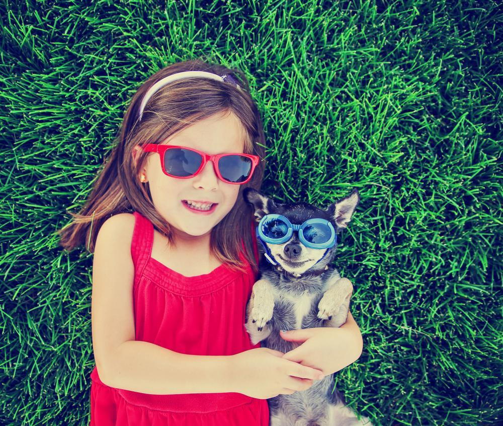girl laying in the grass with her dog wearing sunglasses