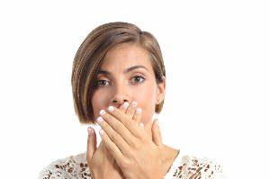 Woman covering her mouth because bad breath