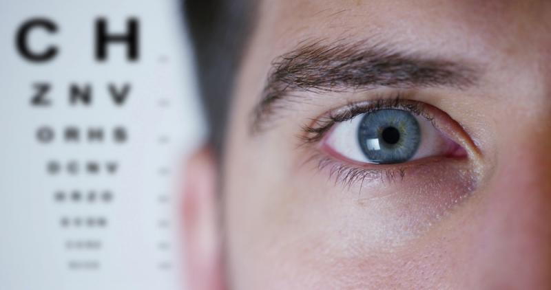 Man in an eye exam in front of an eye chart