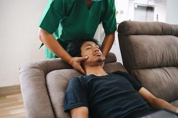 physiotherapist doing neck massages on patient on a a couch