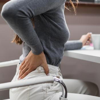 woman with desk job experiencing back pain from bad sitting posture | chiropractic tips for desk job workers