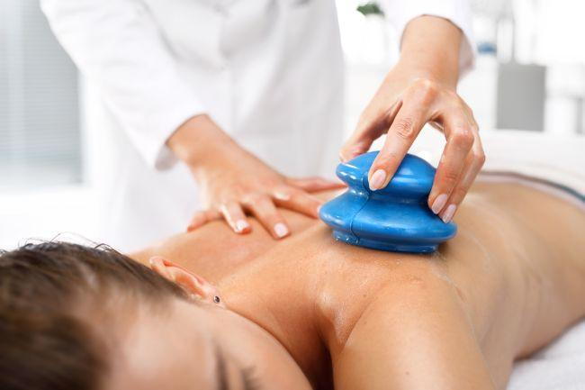Alternative Medicine. Massage. Masseur massaging her back rubber Chinese bubble.