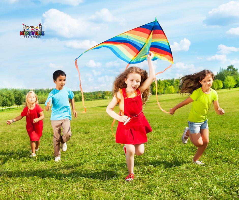 Happy children running together while flying a kite in the sky.