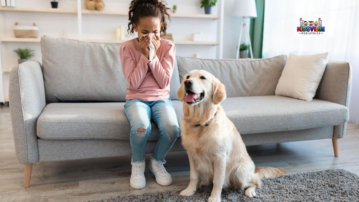 A girl sitting on a couch with a dog beside her on the floor.