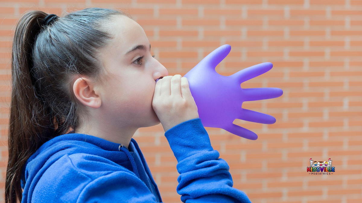 A girl gently blowing on a purple latex glove.