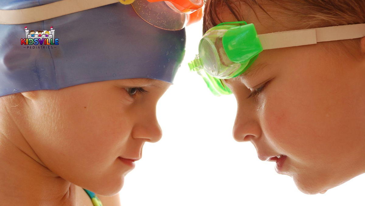 Two children in goggles and swimming caps, ready for a swim.