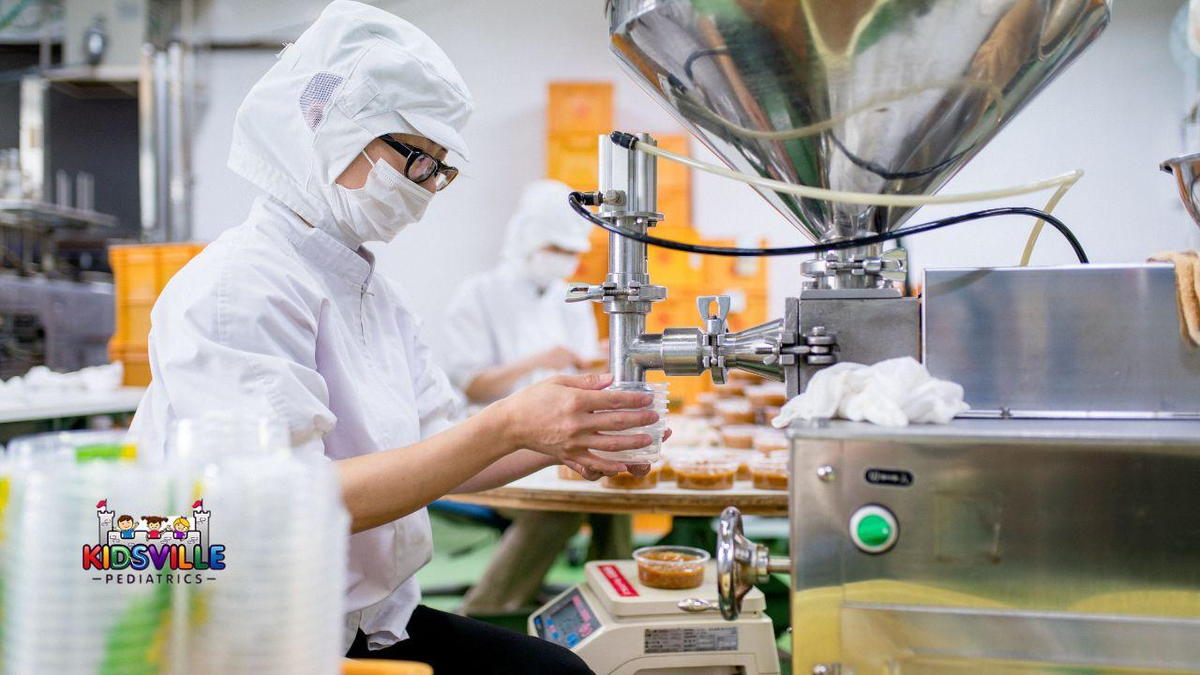 A worker in a food factory assembling products on a conveyor belt.