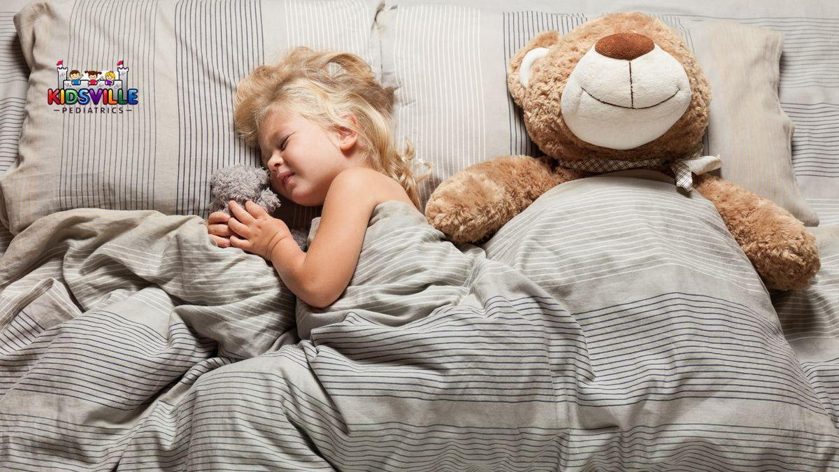 Young girl seemingly having night terror in bed; with her favorite teddy bear by her side.