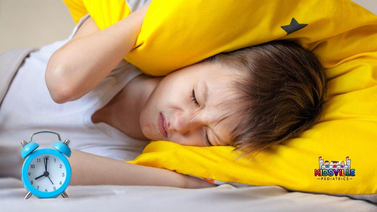 A young kid trying to sleep in bed with a yellow pillow.