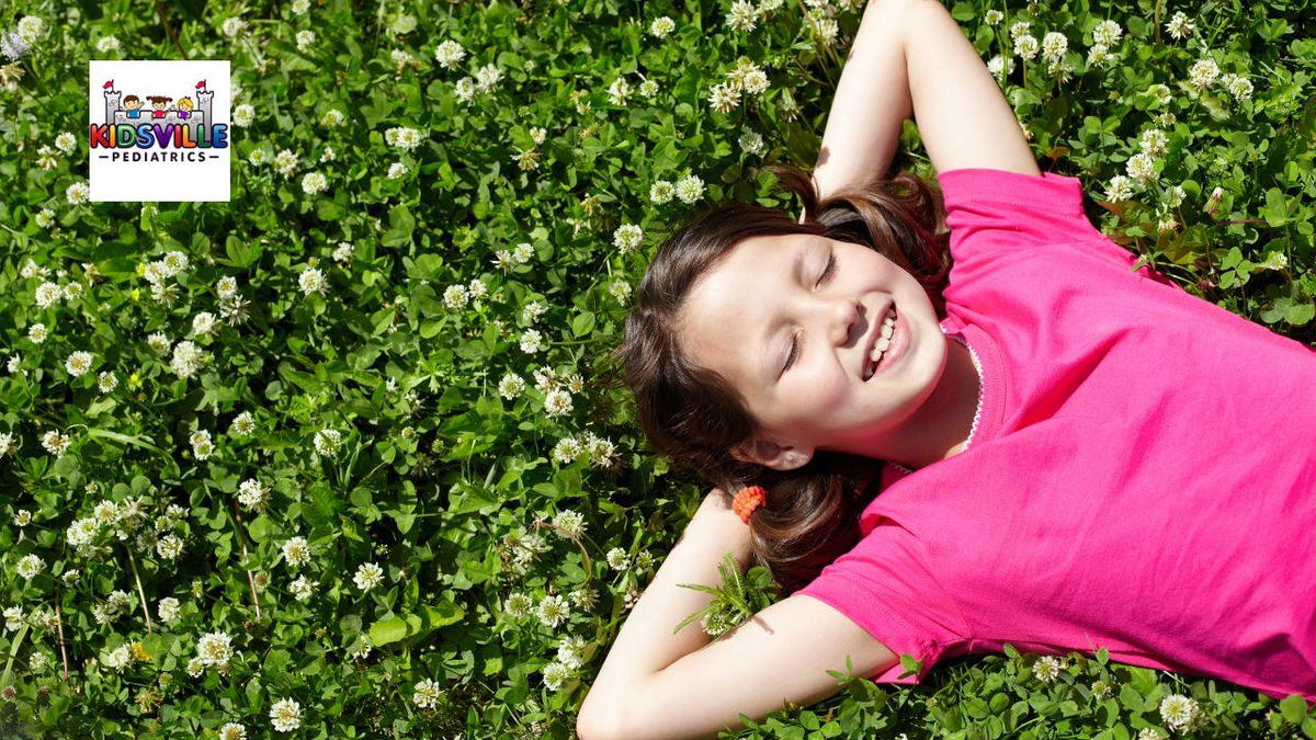 A young girl laying in a field of green grass.