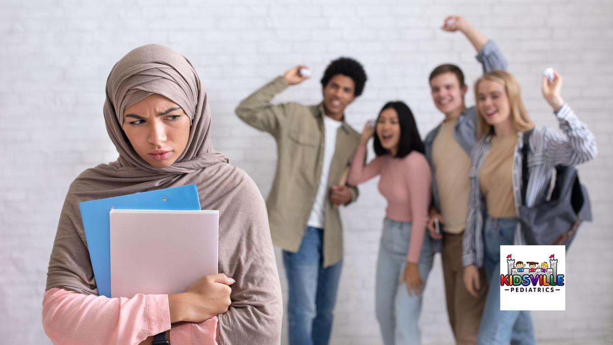 A young woman wearing a hijab holds her books close to her chest as a group of bullies make fun of her.