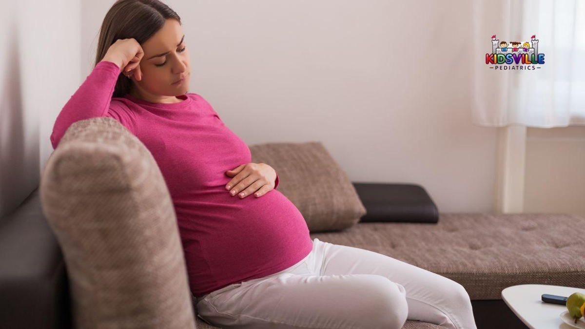 A melancholic pregnant woman seated on a sectional.