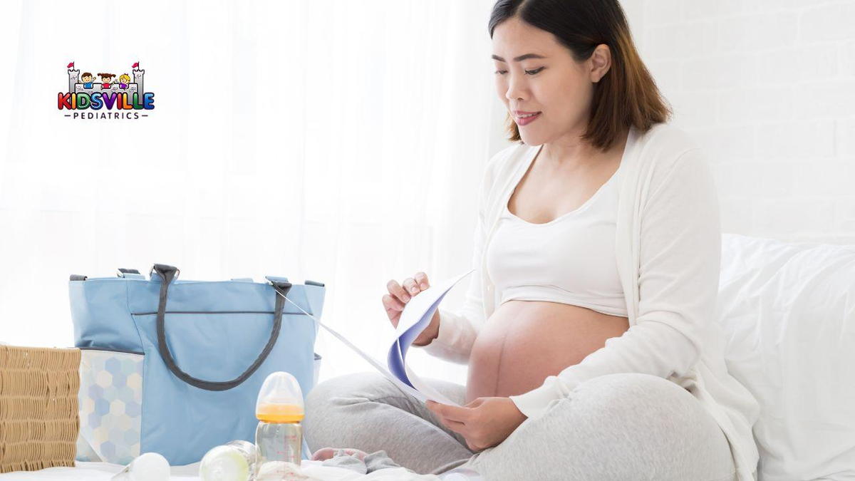 A pregnant woman sits on a bed, thoughtfully looking at a baby bag and birth plan on paper, beside her.