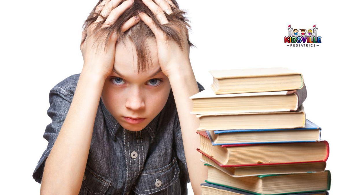 A young boy sits in front of a tall stack of colorful books, with his hands cupping his head, a sign of frustration on his face.