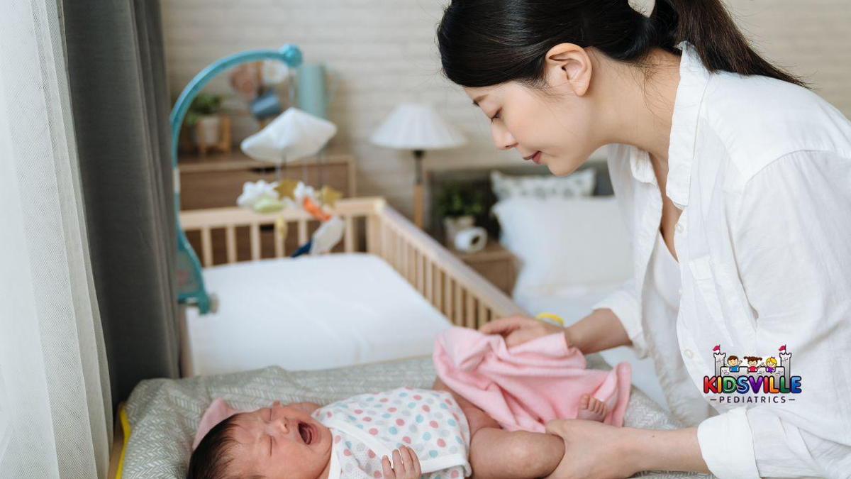 A woman lovingly supports a baby in a crib, as she changes their diaper.