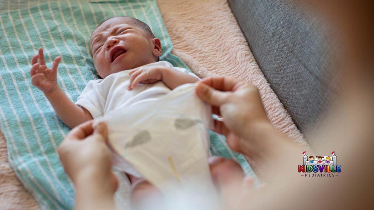 A distressed baby cries as a caregiver prepares to put on a diaper on them.