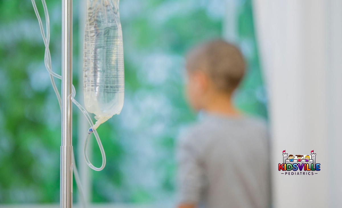 A child gazes out a window as an IV bag hangs on foreground.