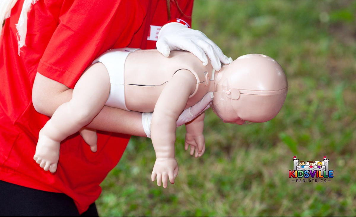 A person holds a baby dummy in their hands, demonstrating CPR.