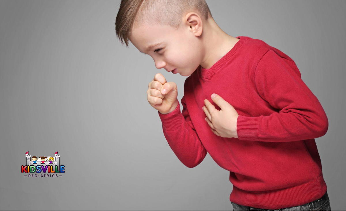 A young boy covers his mouth with his hand as he coughs.