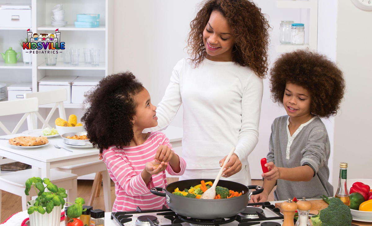 A woman guiding two kids how to cook vegetables over a stovetop.