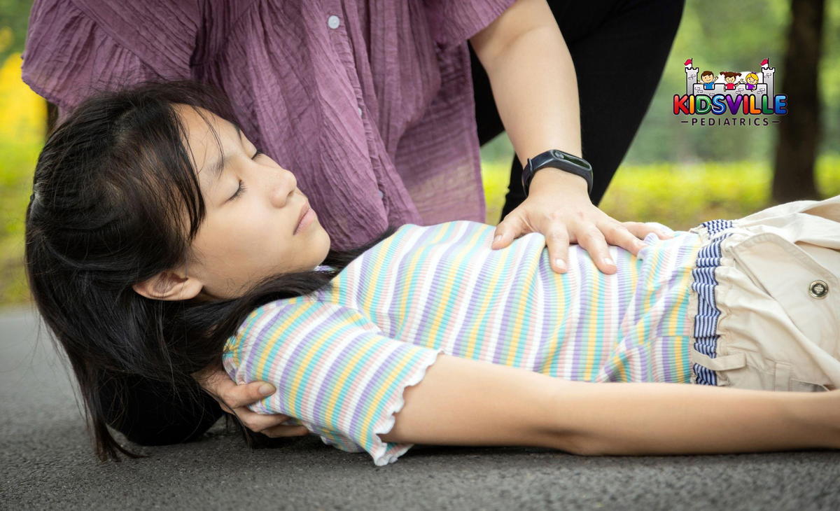 A girl fainted on the floor as a woman assists her.