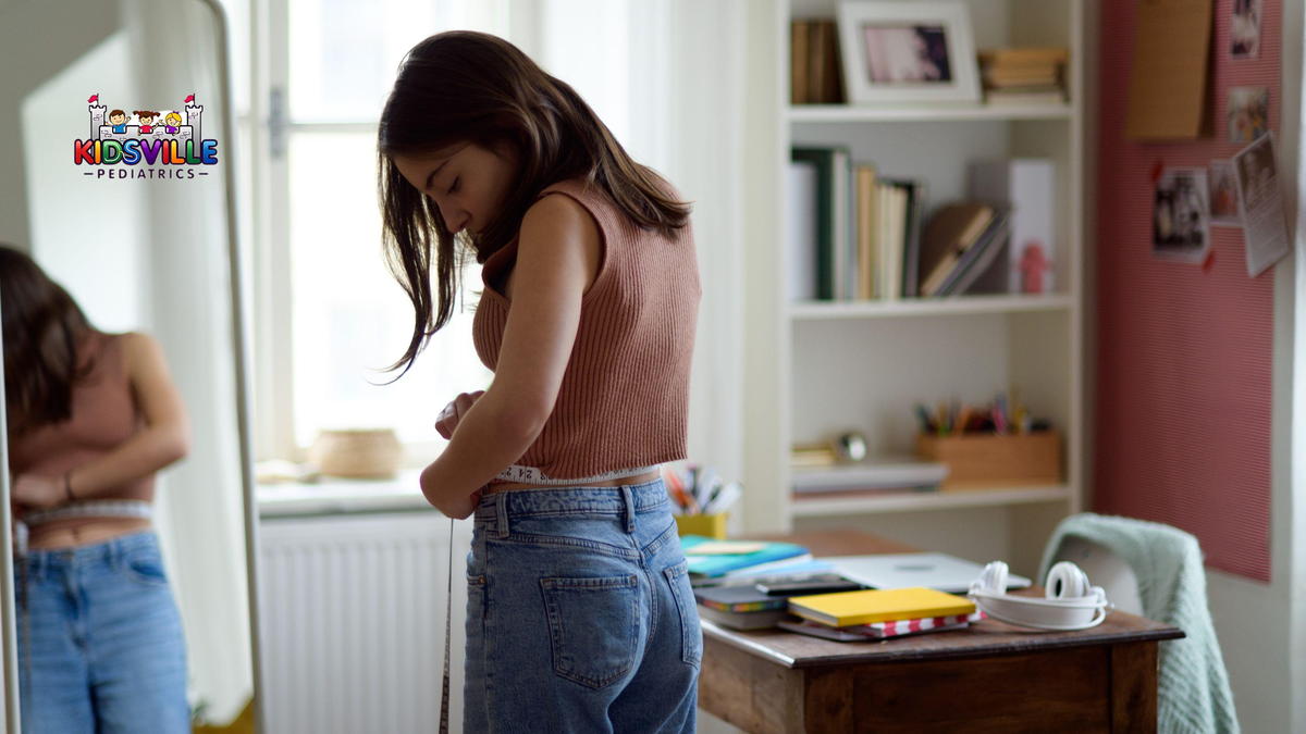 A young woman measures her waistline in front of a mirror.