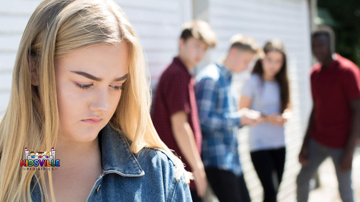 A young woman distanced from a group of teenagers, indicating peer pressure.