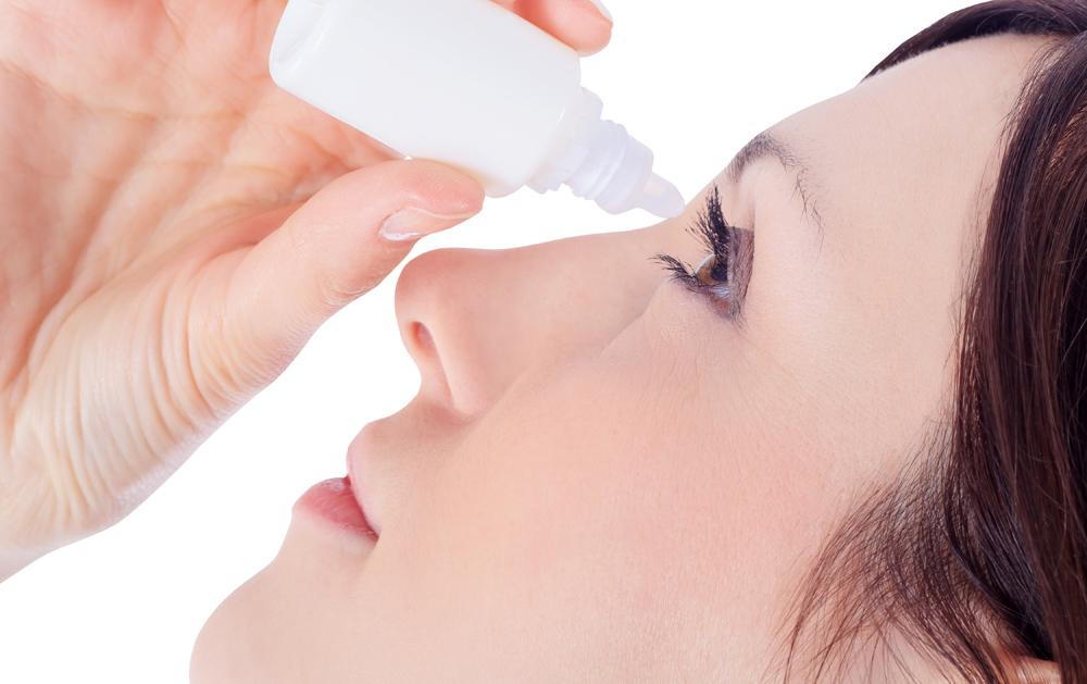 woman using eyedrops because she is suffering from a red eye